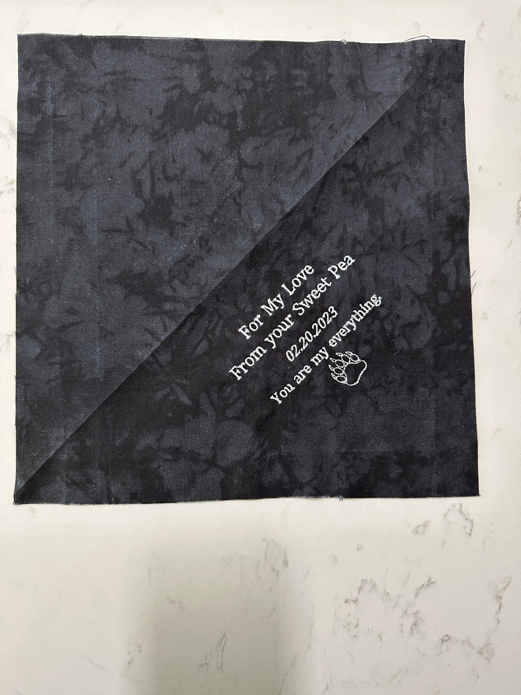 Personalized embroidered quilt label on cotton, featuring custom text in corner layout.