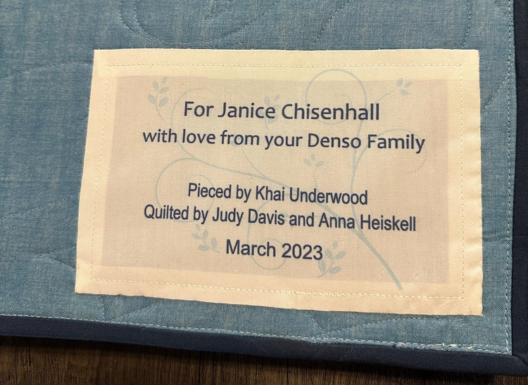 Quilt label with personalized text: 'For Janice Chisenhall, with love from your Denso Family. Pieced by Khai Underwood, Quilted by Judy Davis and Anna Heiskell, March 2023.'