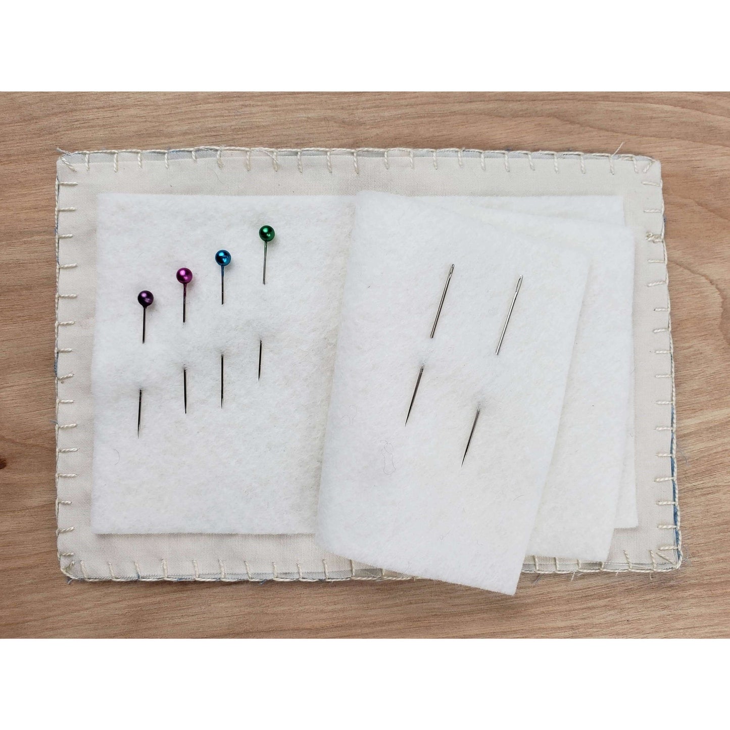 Open boro needle book with colorful pins on wool blend felt pages, part of the Cedar Dell Designs sewing kit.