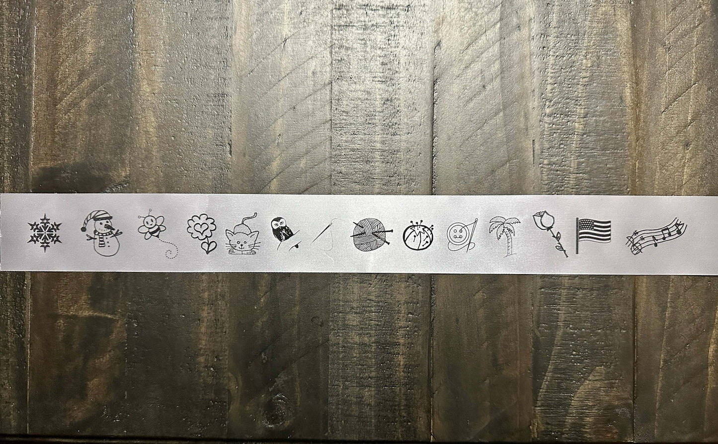 Custom printed satin ribbon with various black icons on a wooden background.