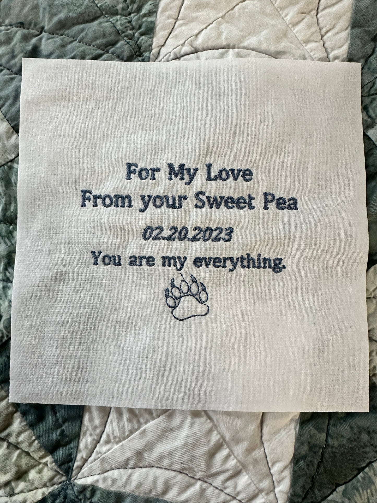 Custom embroidered quilt label with text and paw print, on 100% cotton, featuring a personalized message for a special occasion.