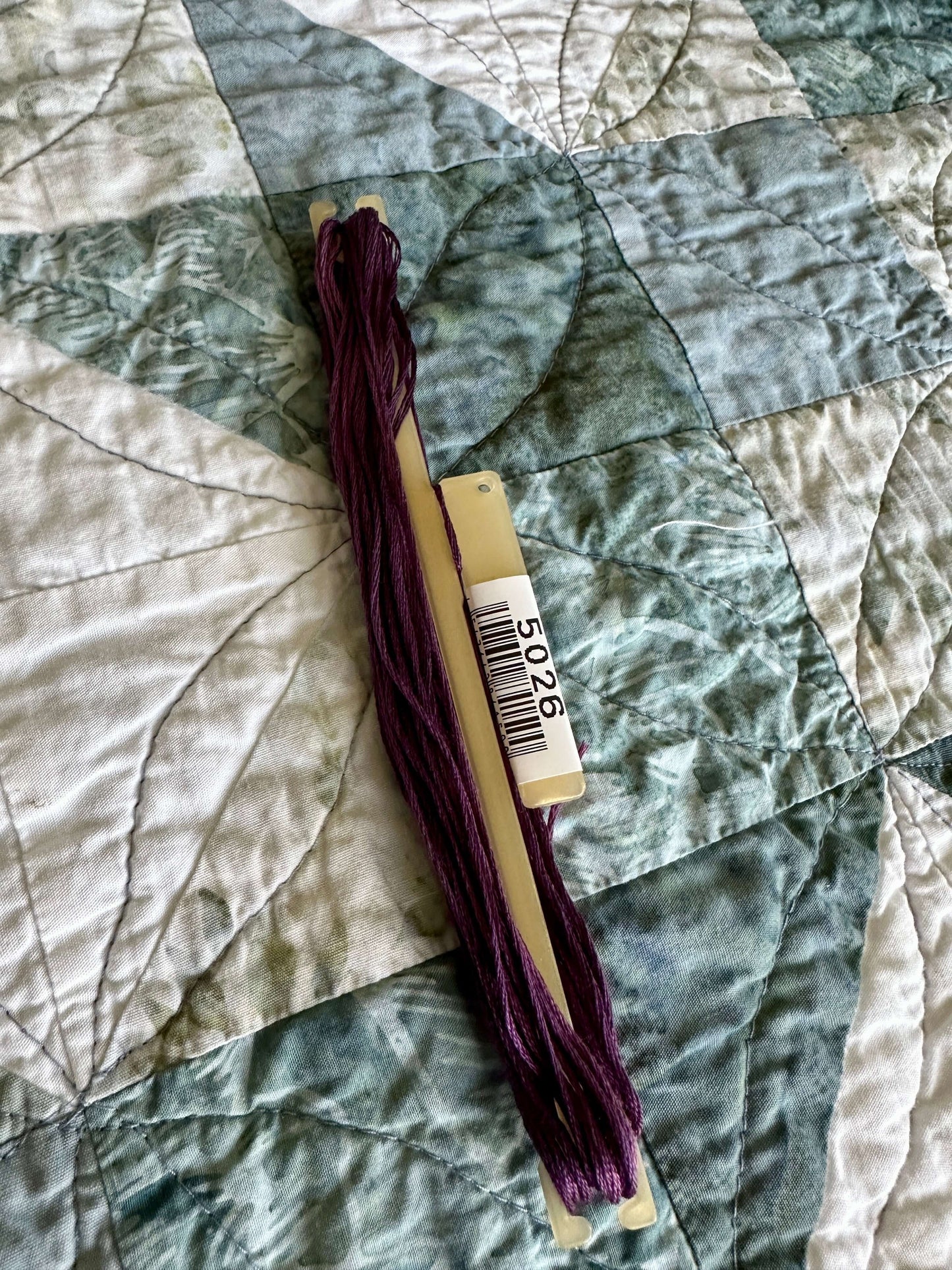 DMC embroidery floss loaded on a StitchBow Floss Holder, displaying vibrant purple color and maintaining full skein shape.