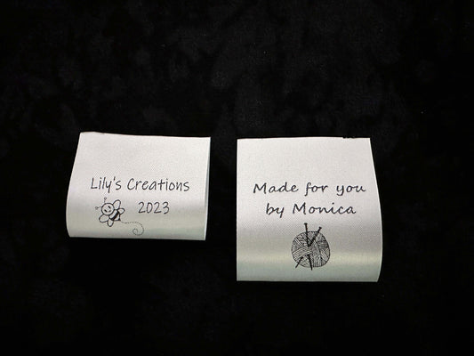 Washable personalized satin ribbon labels in white with black text, featuring custom designs for handmade products.