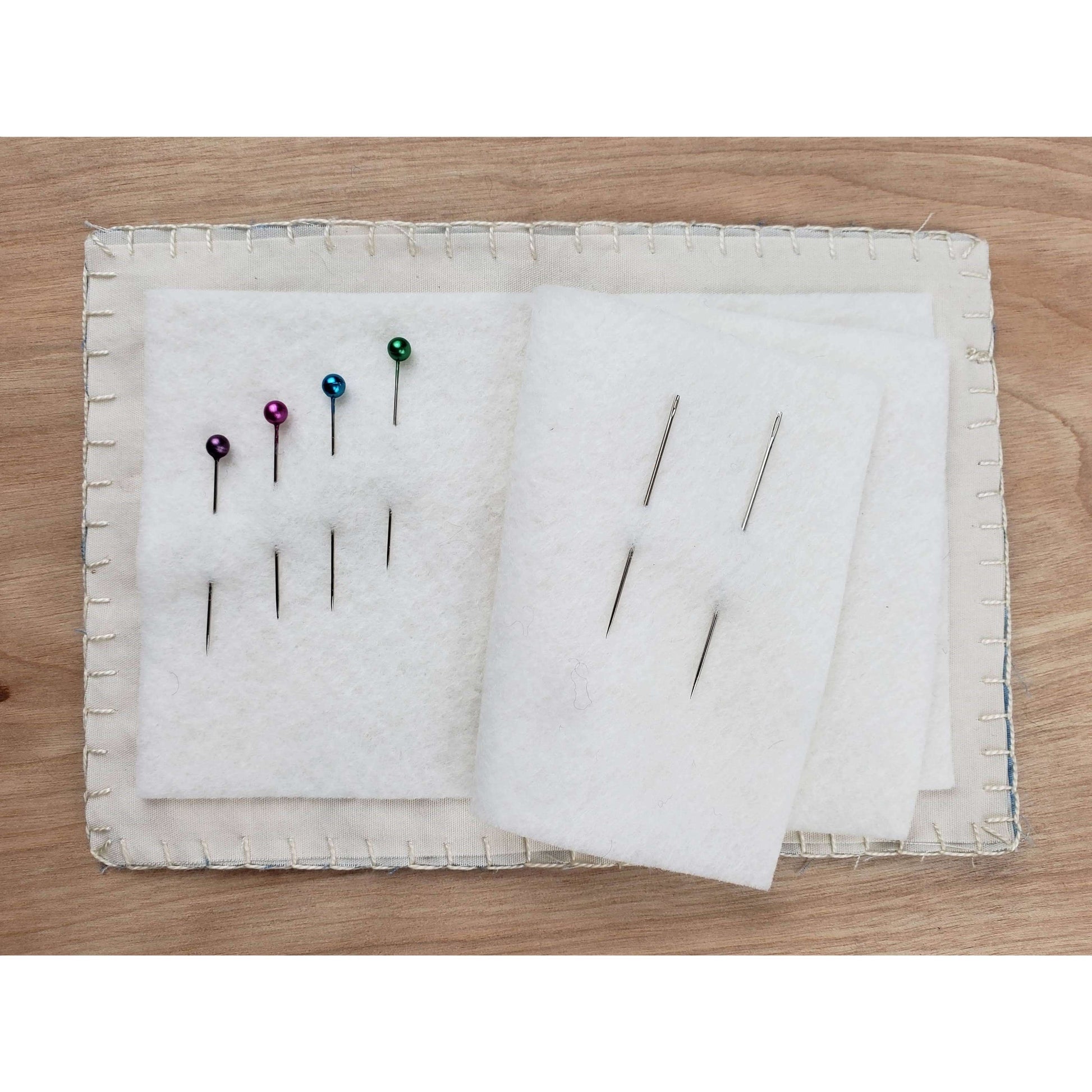 Open boro needle book with colorful pins on wool blend felt pages, part of the Cedar Dell Designs sewing kit.