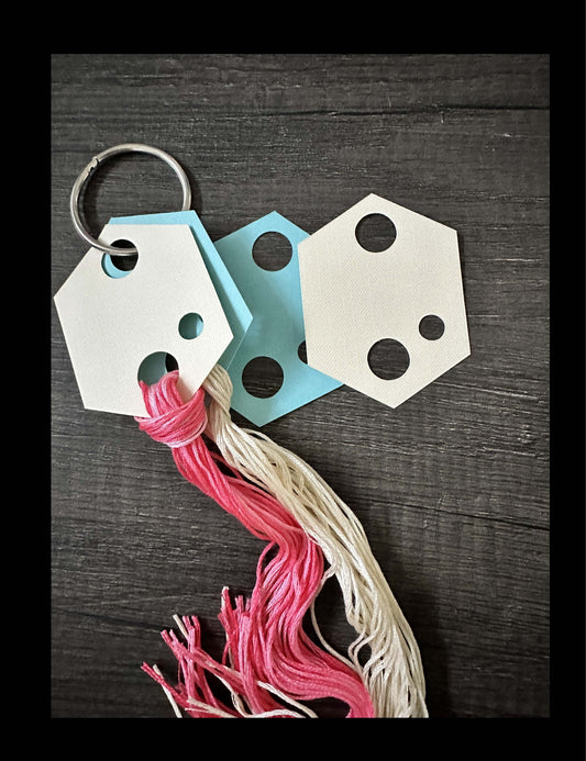 Hexagon embroidery floss holders with pink and white threads, digital download for cross stitch organization, shown on a dark background.