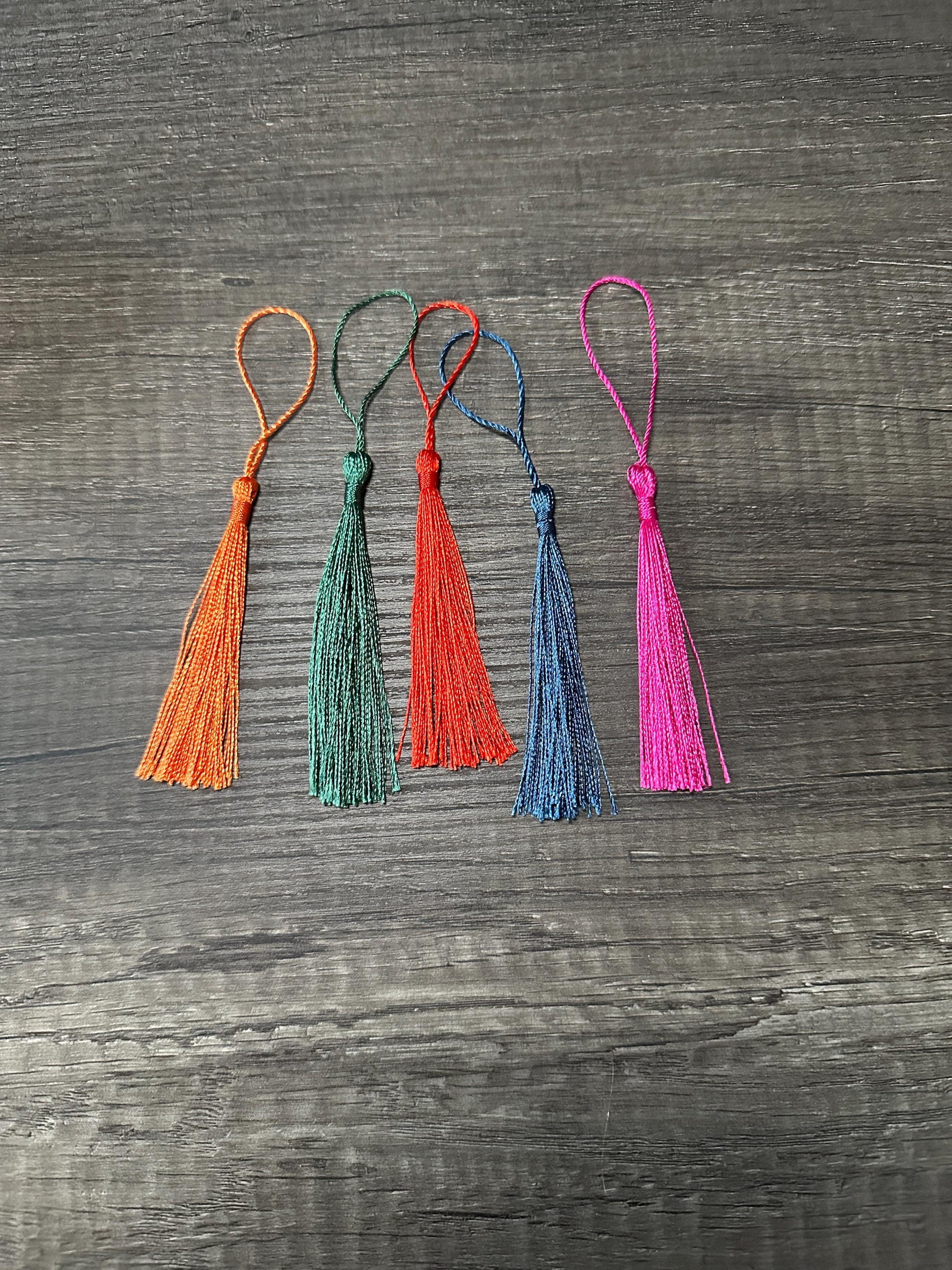 Colorful tassels for Bookmarks Faith Cross Looks Like Stained Glass Amazing Grace, available in orange, green, blue, and pink on wooden background.