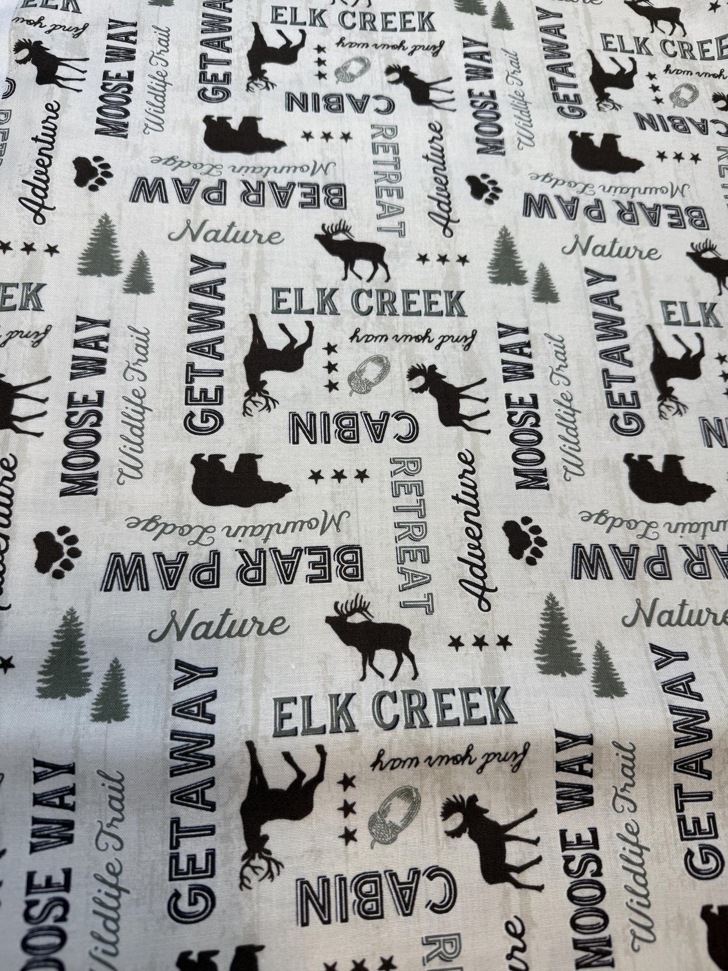 Wildlife Trail 82662-227 Cotton Fabric featuring elk, moose, and forest designs, perfect for nature-themed projects.