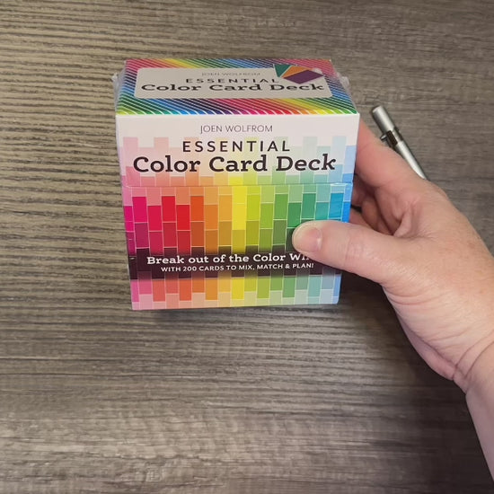 Close-up of a hand holding the Essential Color Card Deck, featuring a colorful box with coordinated color cards for confident color choices.